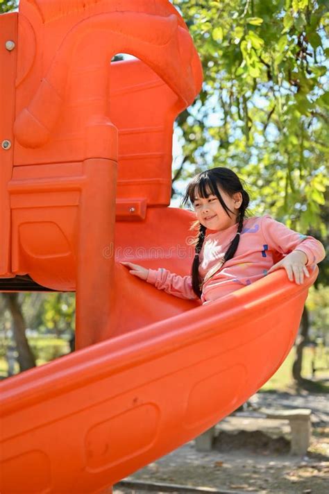 Joyful And Happy Little Asian Girl Playing On Slider Enjoying Outdoor Activity Stock Image