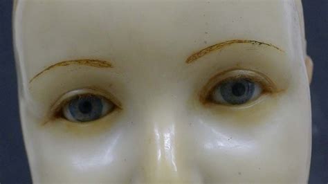 A Closeup Of The Wax Face And Glass Eyes Of An Effigy Of A Young Boy