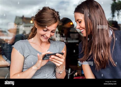 Two Women Having Fun With Their Smartphone On A Terrace Stock Photo Alamy