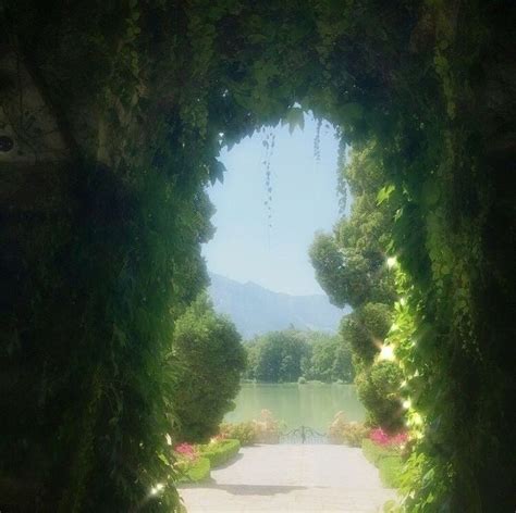 An Archway That Leads To A Lake Surrounded By Greenery
