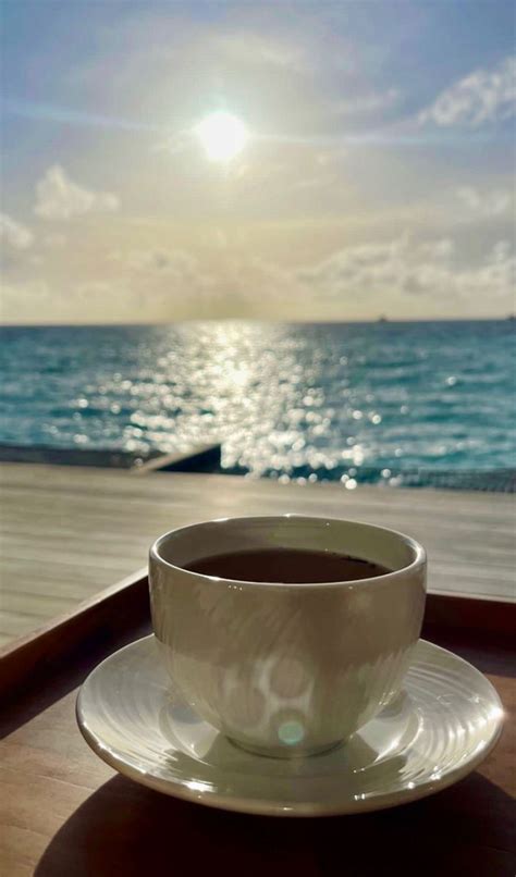 A Cup Of Coffee Sitting On Top Of A White Saucer Next To The Ocean