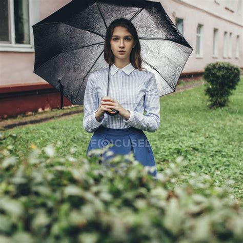 Portrait Of Teenager Holding Umbrella While Standing On Grassy Field