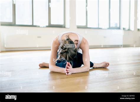 Woman Sits In Yoga Pose Bending Over Stock Photo Alamy