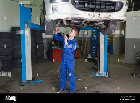 Repairman Working Under Raised Car Stock Photo Alamy