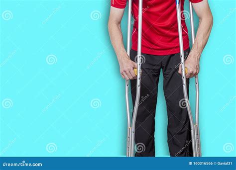 Man On Crutches Isolated On A Blue Background Concept Leg Injuries