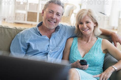 Portrait Of Couple Sitting On Sofa Watching Tv Photo12 Tetra Images