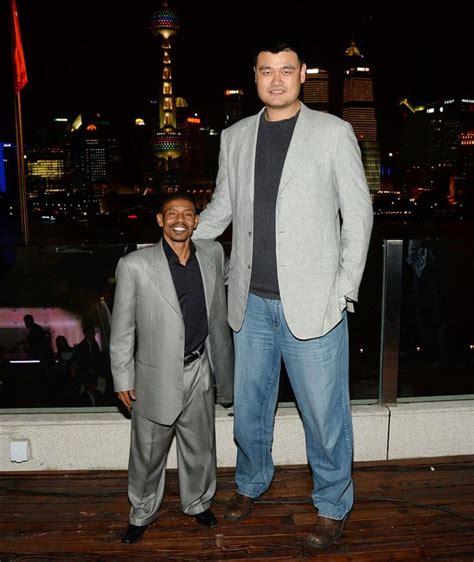 Two Men Standing Next To Each Other In Front Of A Cityscape At Night