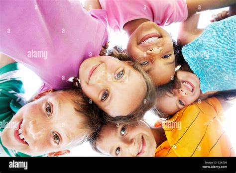 Below View Of Happy Children Embracing Each Other And Smiling At Camera