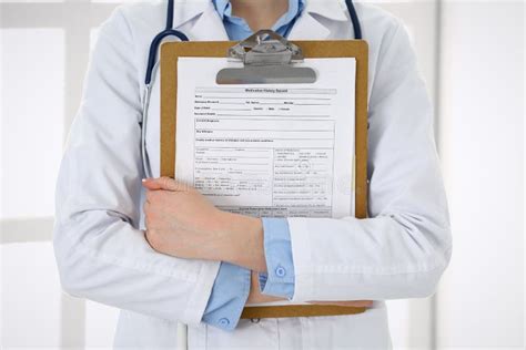 Female Doctor Filling Up Medical Form On Clipboard Closeup Physician