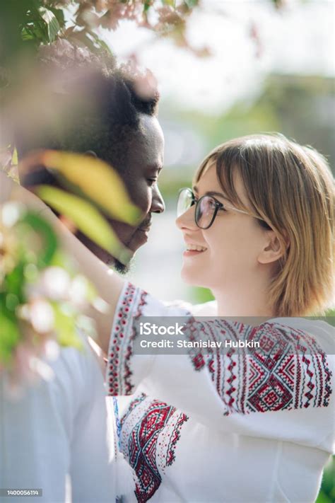 Portrait Of Interracial Couple Embracing In Spring Garden Dressed In