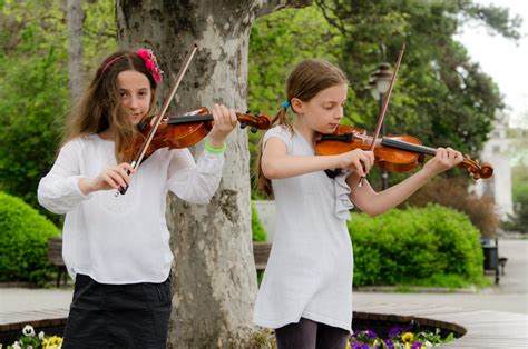 Two child girl play violin in park. Enjoying art and music education ...