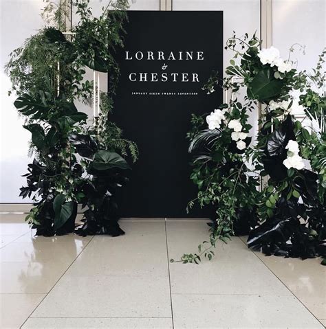 There Are Many Plants In Front Of The Black And White Sign That Says