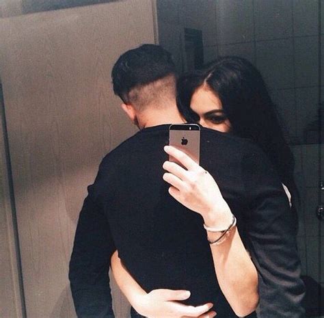 A Man And Woman Taking A Selfie In Front Of A Mirror With Their Cell Phone