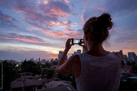 Woman Taking A Picture Of Cityscape At Sunset By Aleksandra Kovac