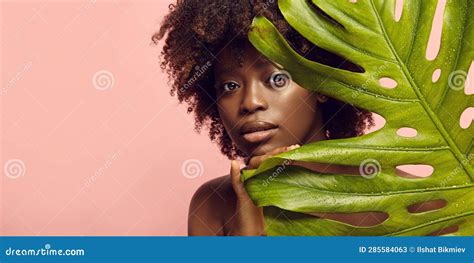 Portrait Of African American Nude Woman Looking Out Of Tropical Leaf