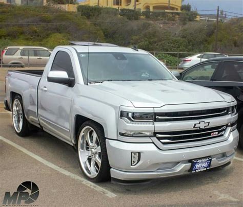 A Silver Truck Parked In A Parking Lot Next To Other Cars And Trucks