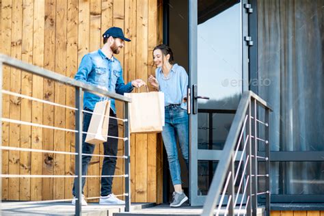 Delivery Man Bringing Goods Home For A Woman Client Stock Photo By
