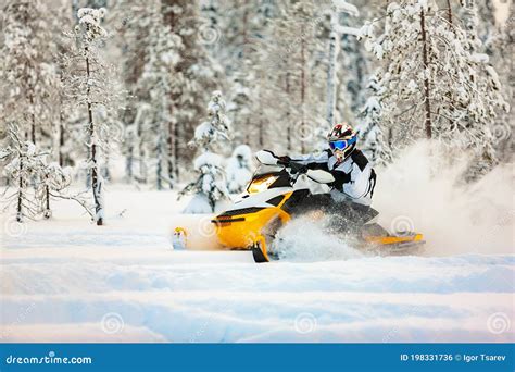 Racer In The Outfit Of A Jumpsuit And A Helmet Driving A Snowmobile By