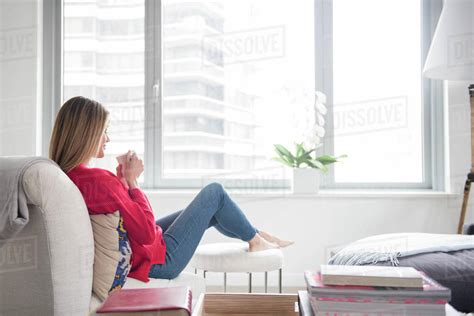 Young Woman Relaxing In Living Room Stock Photo Dissolve