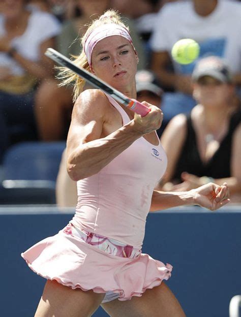A Woman Swinging A Tennis Racquet At A Ball In Front Of A Crowd