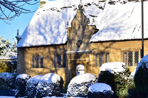 an old english house is all in the snow next to trees and bushes stock image image of
