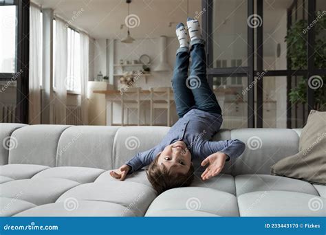 Happy Little 7s Kid Boy Lying On Comfortable Sofa Upside Down Stock