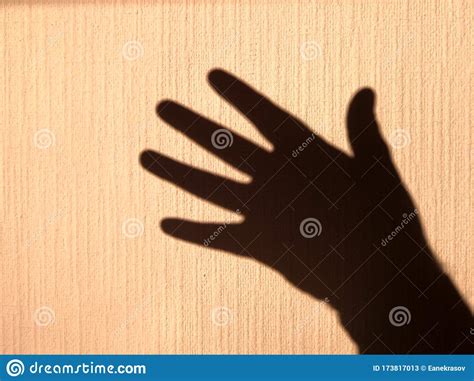 Shadow Silhouette Of A Human Palm On A Yellow Wall