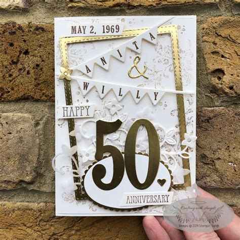 Someone Holding Up A 50th Anniversary Card In Front Of A Brick Wall