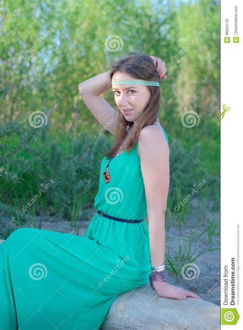 Beautiful Girl Hippie In A Green Dress Sitting On A Log