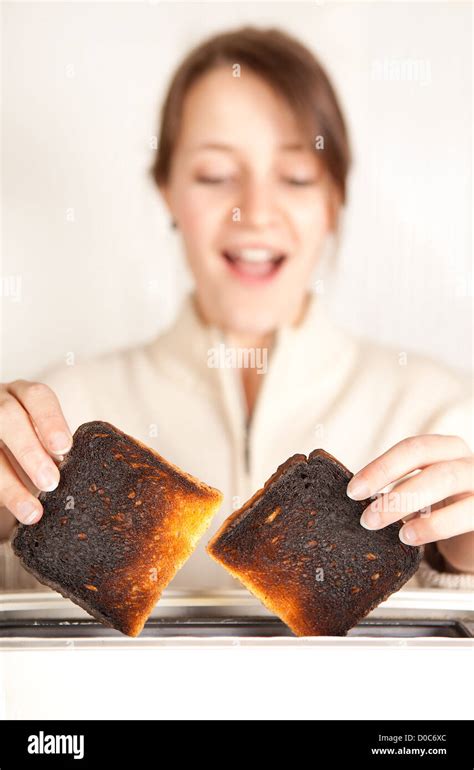 Surprised Woman Taking Burnt Toast Out Of A Toaster Stock Photo Alamy