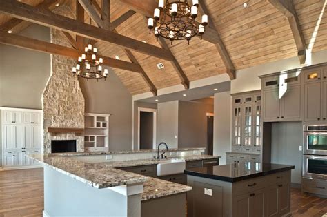White bedroom features a vaulted ceiling accented with dark stained wood beams illuminated by wrought iron candelabra chandeliers over a an arched niche filled with a white tufted. LOVE this kitchen,family room combo...and I might add, the ...