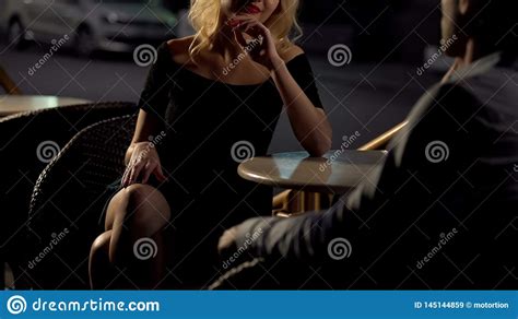Attractive Blond Female Seducing Man On Restaurant Terrace Escort