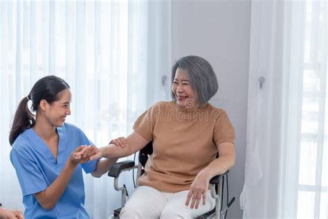 Young Nurse Taking Care Elderly Disabled Woman Sitting In A Wheelchair With Copyspace Stock