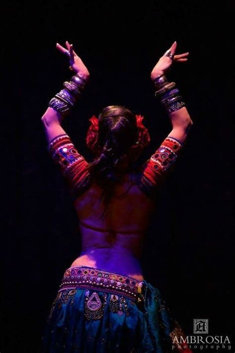 A Belly Dancer Performing In The Dark With Her Hands Up And Arms Outstretched To The Side