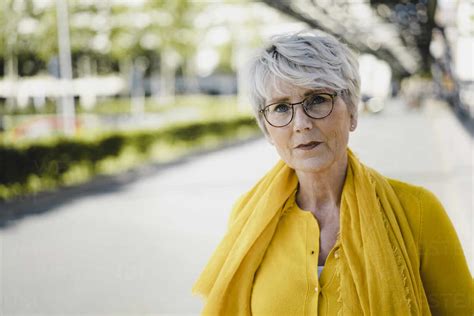 Portrait Of Mature Woman With Grey Hair Wearing Glasses And Yellow