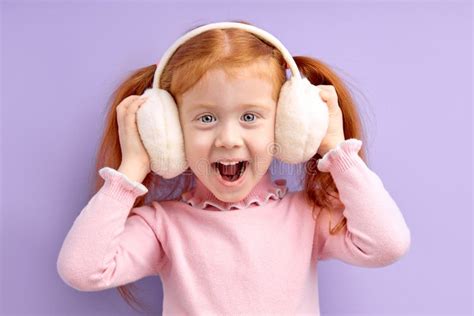 Happy Little Girl With Red Hair Stand Wearing Wireless Headphones