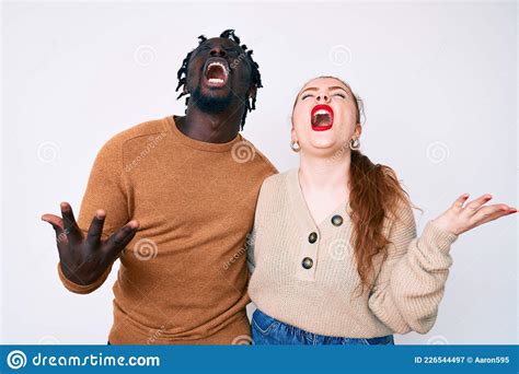 interracial couple wearing casual clothes crazy and mad shouting and yelling with aggressive