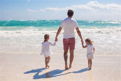 Vista Trasera Del Padre Y Sus Dos Hijas Lindas Caminando En La Playa De