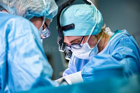 Surgeon Performing Surgery In Hospital Operating Room Surgeon In Mask Wearing Loupes During