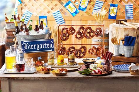 a table filled with pretzels beer and other foods on display in front of a wooden fence