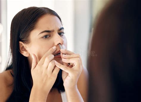 Face Nose And Beauty With A Woman Using A Tweezer To Remove Nasal Hair In The Bathroom Of Her