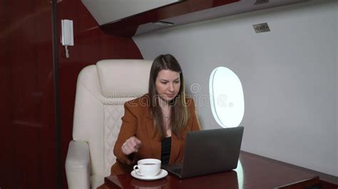woman in airplane working at laptop and drinking coffee businesswoman in private jet or first