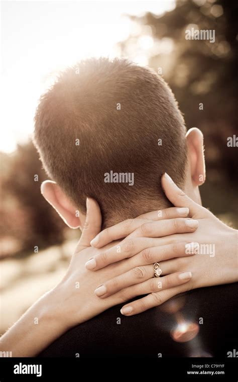 A Woman Hugs Her Fiance By Placing Her Hands Around His Neck In Sepia