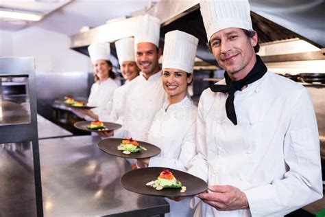 Happy Chefs Team Standing Together In Commercial Kitchen Stock Photo