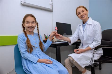 doctor and little patient during medical checkup friendly female pediatrician giving candy to