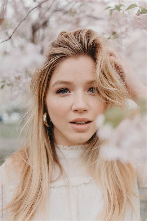 A Young Blonde Woman Standing Amongst The Cherry Blossom Trees By