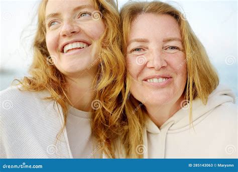 redhead senior mother and her beautiful adult daughter are walking together and laughing stock