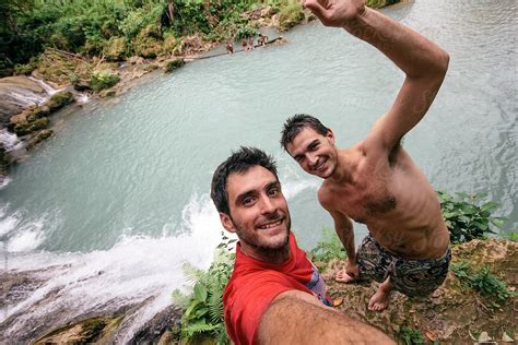 Two Young Man Friends Selfie On Top Of A Cliff On A River Pond In Tropical Island By Stocksy