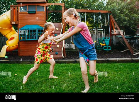 Portrait Of Two Little Girls Sisters Fighting On Home Backyard Friends