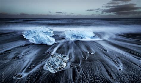 Black Sand Beach In Iceland Is Dotted With Turquoise Icebergs